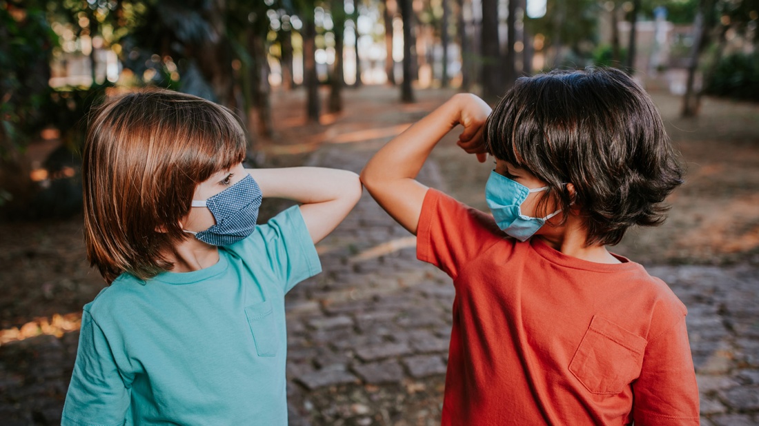 Kinder  begrüßen sich mit Abstand in der Corona Pandemie