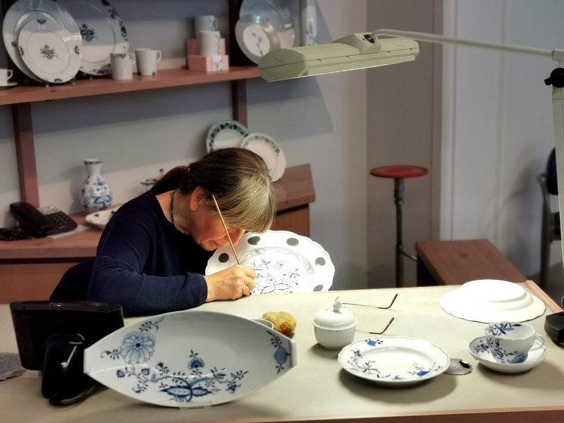 Eine Frau malt mit einem Pinsel auf einen Teller in ihrer Hand