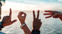 Die Buchstaben LOVE mit Fingern geschrieben vor einem Sonnenuntergang