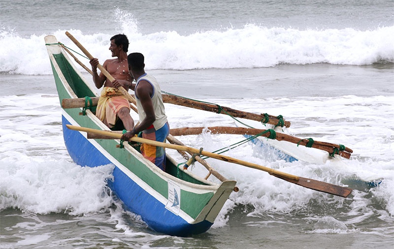 Fischer in Boot in Brandungswellen in Sri Lanka