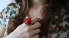 Nahaufnahme einer Frau, die eine vertrocknete Rose in den Händen hält.