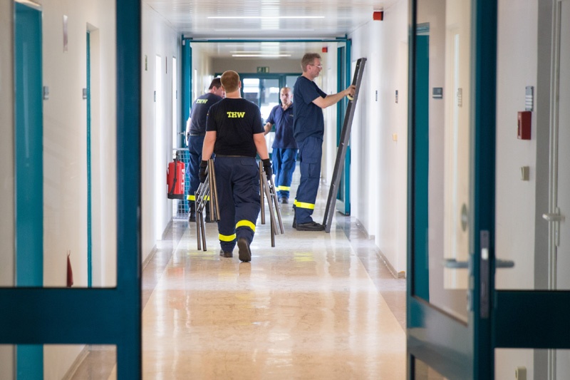 In Berlin-Karlshorst bauen Polizisten sowie Helfer vom THW und DRK Betten in einer neuen Flüchtlingsunterkunft auf. 