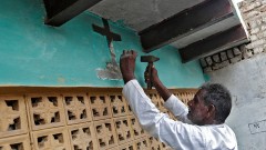 Ein Mann schlägt das Kreuz über seiner Haustür ab, nachdem er vom zum Christentum zum Hinduismus konvertiert ist.