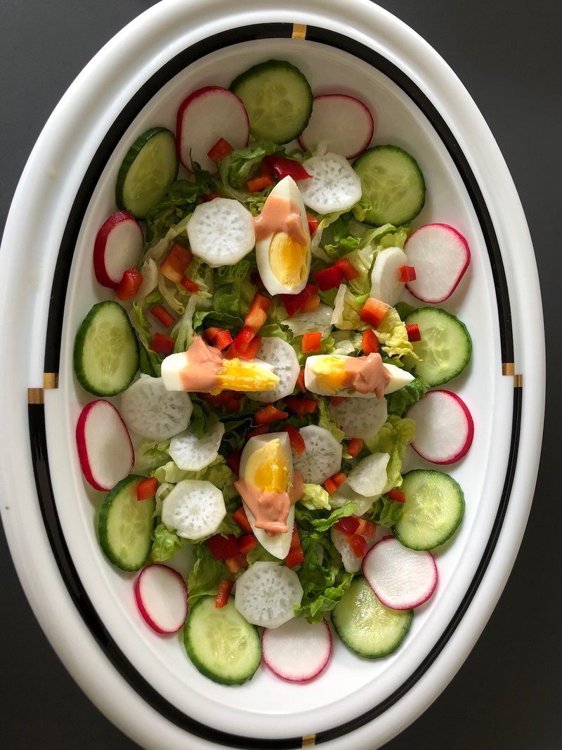 Eine Porzellanplatte mit grünem Salat und viel Rohkost