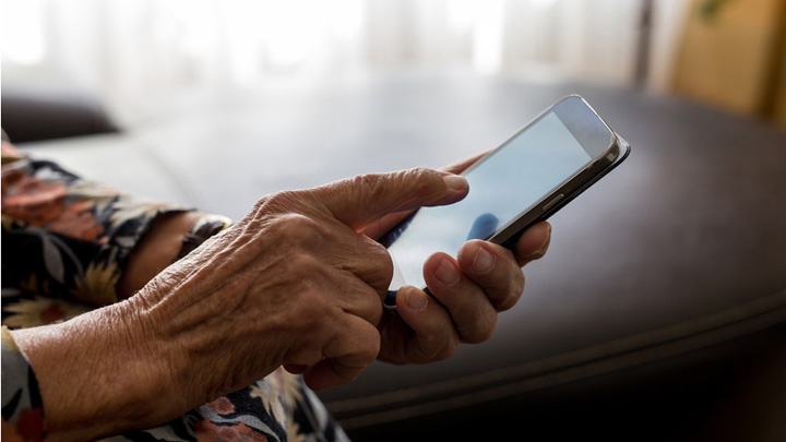 Eine alte Frau wählt eine Nummer auf einem Mobiltelefon.