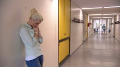 Julia wartet mit besorgtem Blick im Schulflur