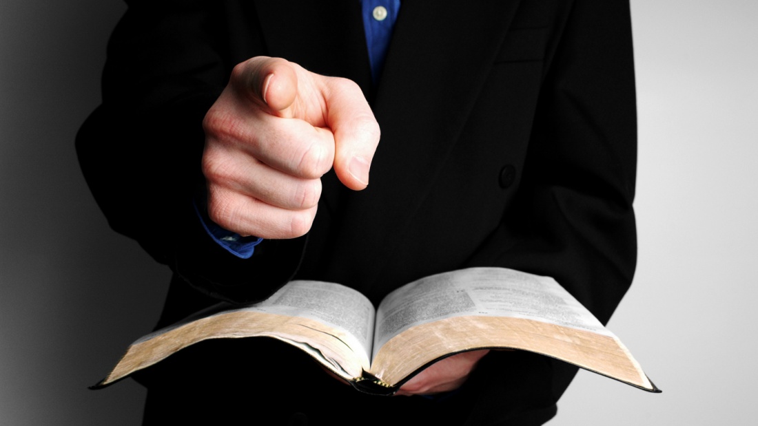 Ein Mann hält die Holy Bible in eine Hand und zeigt mit dem Zeigfinger der anderen Hand auf den Betrachter.