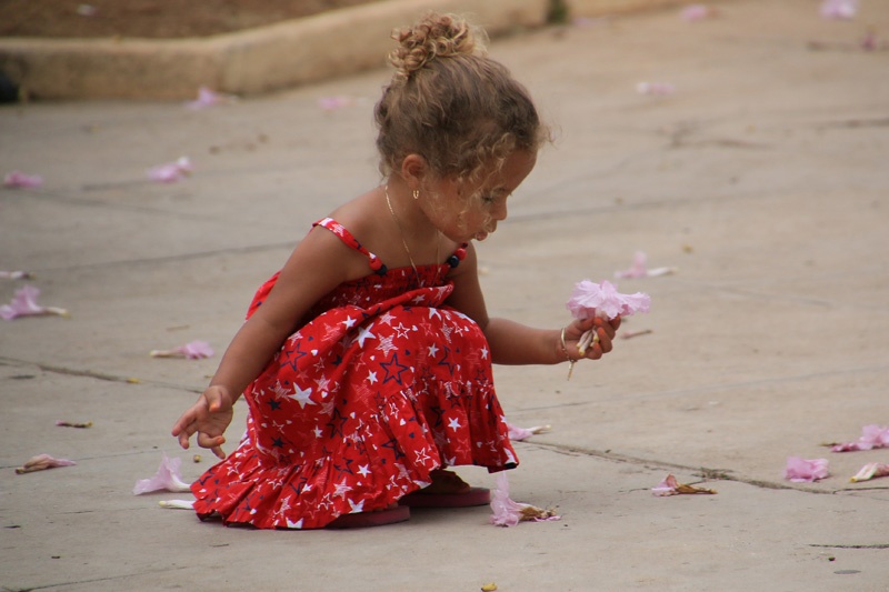 Ein kleines Mädchen mit einer Blüte in der Hand.