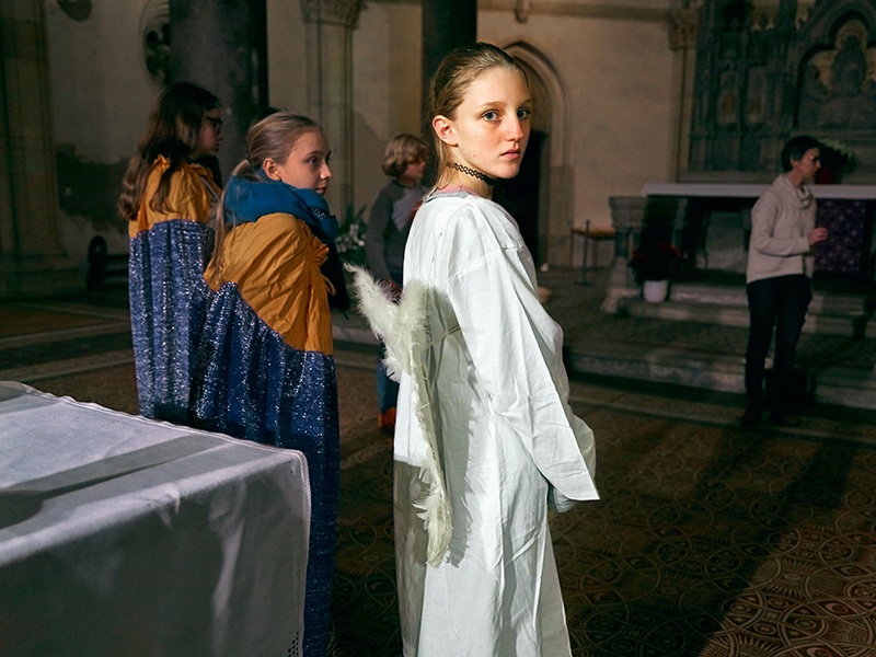 Ein junges Mädchen im Engelskostüm steht während der Probe fürs Krippenspiel in der Kirche