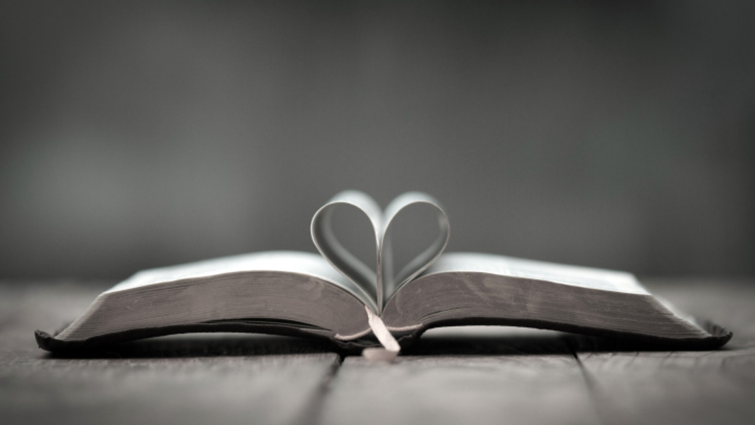 Zwei Seiten einer aufgeklappten Bibel bilden ein Herz