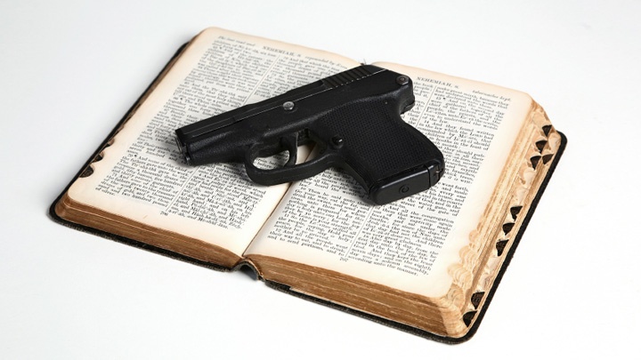 Eine Waffe liegt auf einer Bibel.