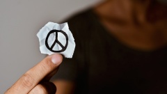 Ein Mann hält ein Stück Papier mit einem Peace-Zeichen in der Hand.