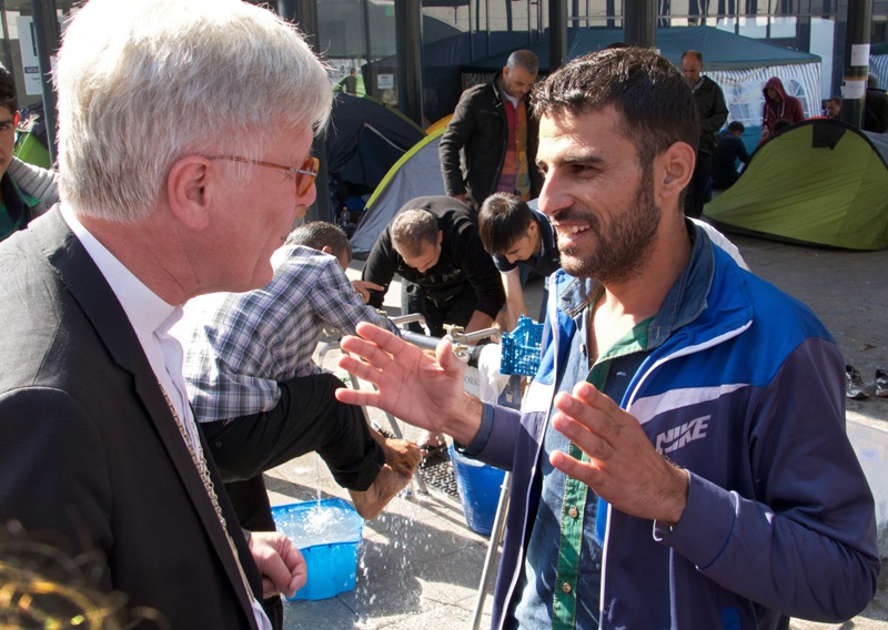 Heinrich Bedford-Strohm spricht am Sonntag, dem 13. September 2015, im Budapester Ostbahnhof mit einem Flüchtling aus Syrien.