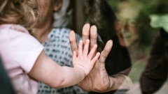  Hand von Enkel und Großmutter an Scheibe