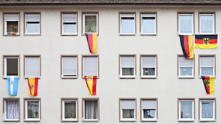 Nationalflaggen verschiedener Länder hängen an Fenstern eines Mehrfamilienhauses.