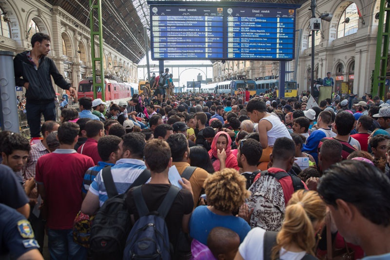 Flüchtlinge stehen vor den Polizeiabsperrungen vor dem Bahnsteig 8. Sie wollen mit dem Zug nach München, für den Sie auch Fahrkarten erworben haben. Doch trotz ihrer Zugtickets muss die Polizei ihnen die Weiterreise nun verwehren.