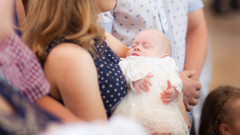 Baby auf dem Arm einer Frau bei der Taufe.