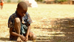 Ein Kind hat  in Khulubvi im Süden von Malawi bei einer Lebensmittelverteilung Maiskörner aufgesammelt (Archiv).
