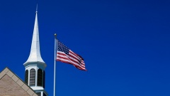 US-amerikanische Flagge vor einem Kirchturm.