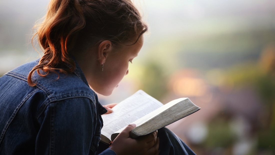 Kind liest in Bibel