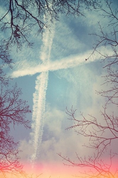 Kondensstreifen von Flugzeugen bilden ein Kreuz am Himmel.