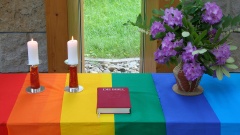 Trauung am mit Regenbogenfahne geschmücktem Altar 