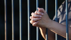 Gefaltete Hände hinter Gittern