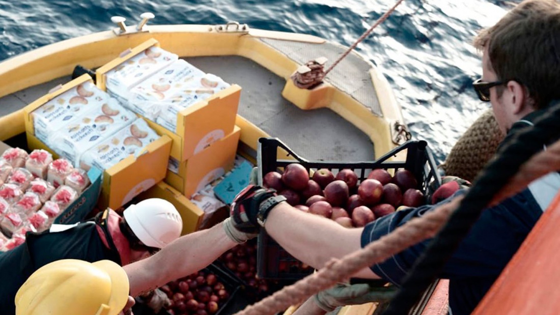Notfallversorgung der italienischen Seefahrtsbeamten, die Lebensmittel an ein Besatzungsmitglied an Bord des Schiffes "Aquarius" überreichen. 