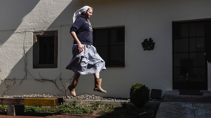 Schwester Clara springt im Garten des Kapuzinerkloster Stühlingen nach getaner Arbeit von einer Bank.
