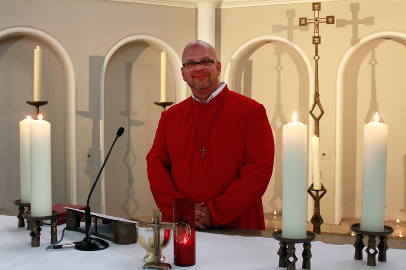Bruder Franziskus in rotem Habit hinter dem Altar