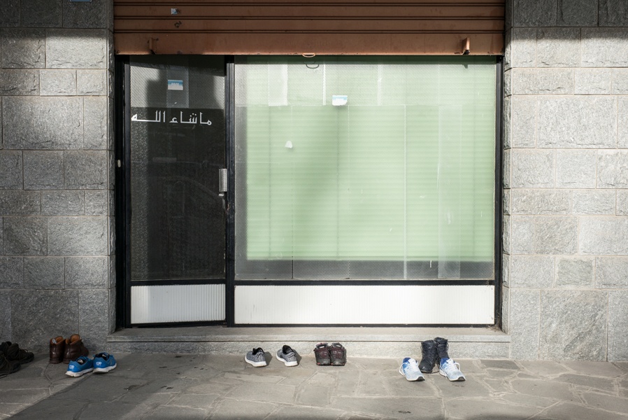 Vor einem Schaufenster mit einem arabischen Schriftzug stehen sechs Schuhpaare.