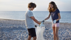 Jugendliche sammeln Plastikmüll am Strand ein