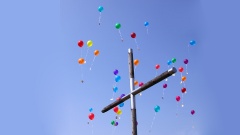Kreuz vor Himmel mit Luftballons