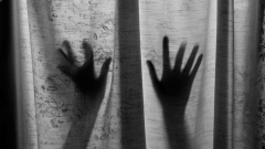 Schatten zweier Hände hinter einem Vorhang.