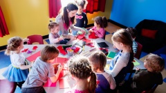 Kindergärtnerin spielt mit Gruppe von 6 Kindern 