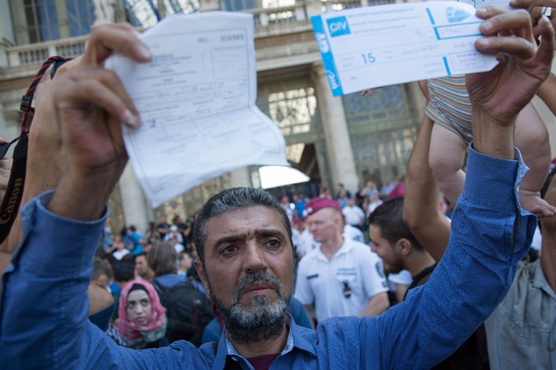 Mit Zugtickets in der Hand protestieren Flüchtlinge vor dem Bahnhof Budapest Keleti dafür, Züge nach Deutschland nehmen zu dürfen.