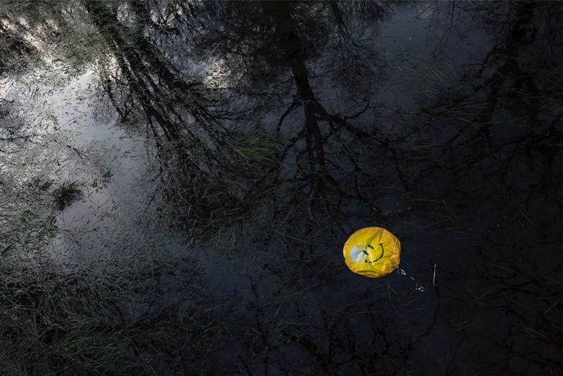 Ein gelber Ballon mit Smiley treibt im Wasser.