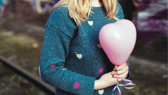 Junge Frau hält einen herzförmigen Luftballon in den Händen.