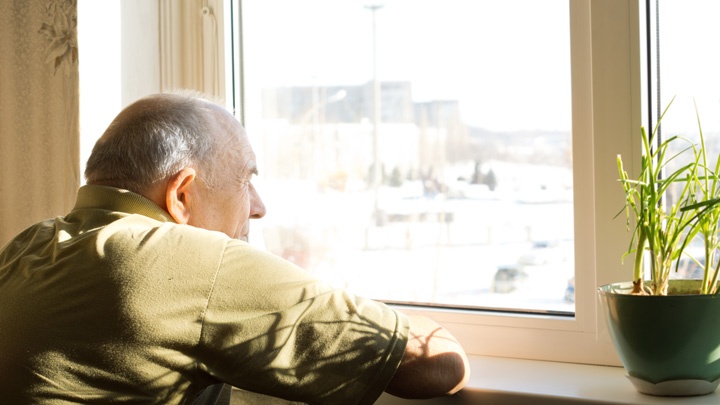 Ein älterer Mann blickt aus dem Fenster.
