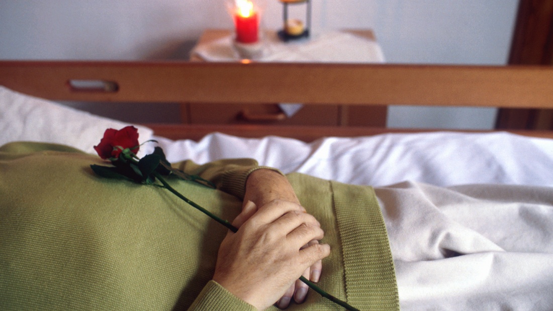 Frau im Sterbebett mit Kerze