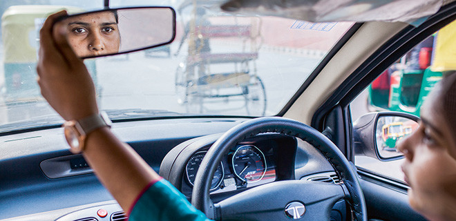 Die indische Taxifahrerin Seema blickt in den Rueckspiegel ihres Wagens 